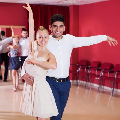 Happy adult couples enjoying latin dances in modern studio